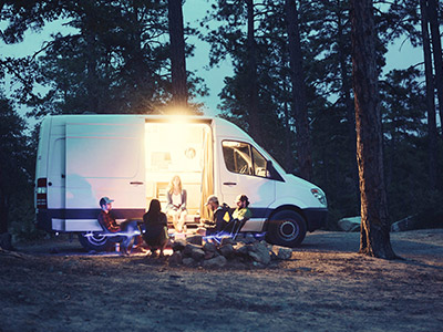 3 RV batteries and a Noco charger siting in front of a camper attached to a truck