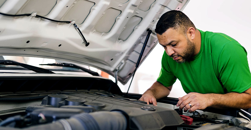 Man in green shirt looking at car battery