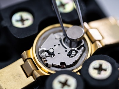 watch battery placed into watch with tweezers