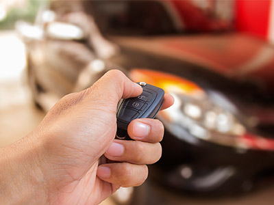 Hand holding keyfob unlocking black car