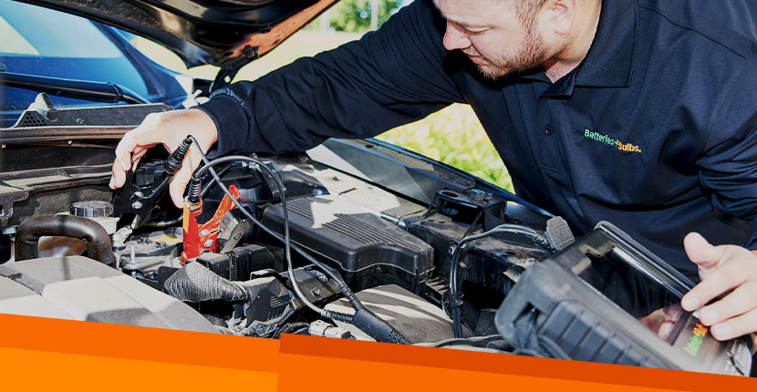 Employee attaching jumper cables to a car battery