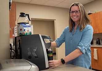 Corporate employee in the kitchen making coffee